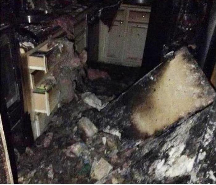 Kitchen with extreme fire damage with building materials strewn around