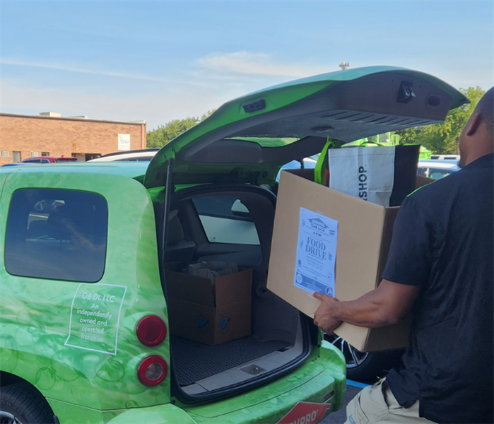 Male SERVPRO employee loading the car up with donations 